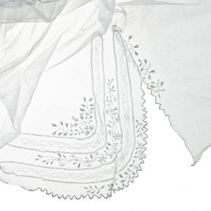 1056 etnografia - fragment chusty czepcowej, szerzyny, wyrób fabryczny, na biały delikatny tiul  naniesione są ornamenty znajdujące się w trzech narożnikach chusty, wys. 120, szer. 120 cm